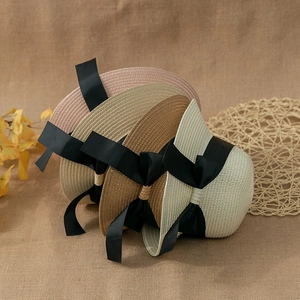 Detail shot of woven straw sun hats with large black bows in multiple colors