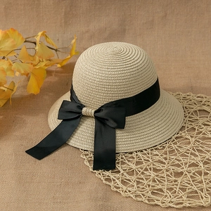Detailed close-up of beige straw hat with elegant black satin ribbon and bow accent