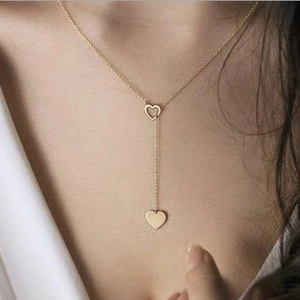 Close-up of golden double-layer Y-necklace featuring hollow and solid heart pendants