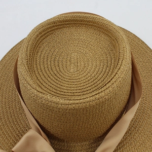 Detailed top view of brown woven straw hat showing intricate texture and satin ribbon