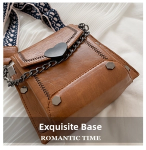 Detailaufnahme der braunen Ledertasche mit schwarzer Herzschließe und Metallkette