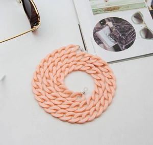 Detail view of pink acrylic eyewear chain with silicone loops on lifestyle background