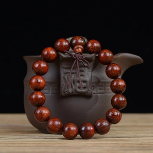 Dettaglio macro di perle in legno di sandalo rosso con venature naturali e punti dorati
