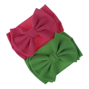 Detail of rose red and green baby headbands with oversized bow in textured bullet fabric