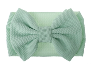 Detailed view of mint green baby headband featuring soft ribbed fabric and large bow