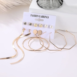 Close-up of 6-pair gold earring set with pearls and geometric shapes on white props