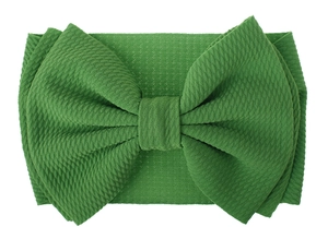 Detail of green oversized bow headband featuring soft waffle knit texture and fabric
