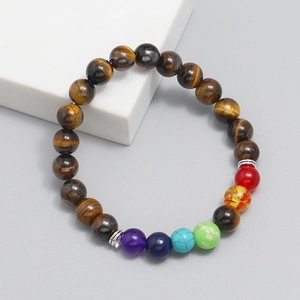 Tiger eye stone beaded bracelet with colorful accents on a minimalist grey background