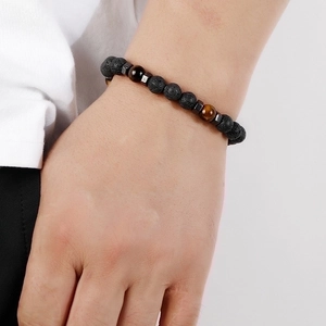 Detail shot of 8mm black lava rock and tiger eye beaded bracelet on a person's wrist
