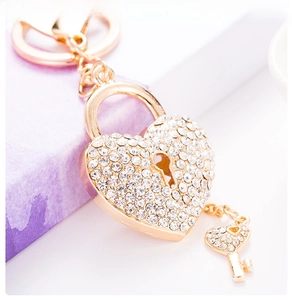 Close-up of heart-shaped lock keychain with sparkling crystals on a purple gift box