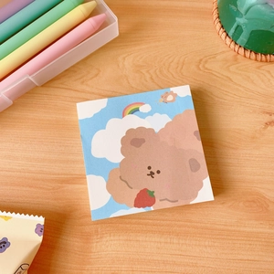 Cute brown bear memo pad with rainbow background on a wooden desk with crayons