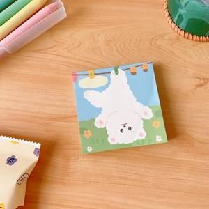 Detail view of cute cartoon dog illustration on square green and blue sticky notes
