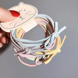 Dettaglio di elastici per capelli colorati con fiocco in toni Morandi su cartoncino