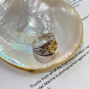 Détail d'une bague vintage en argent 925 avec fleurs placée dans un coquillage