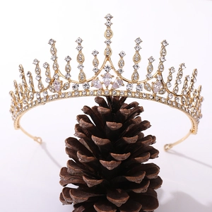 Detailed close-up of a gold bridal crown with zircons resting on a pine cone