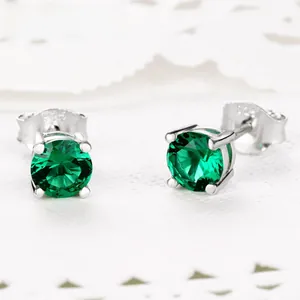 Détail macro de boucles d'oreilles émeraude en argent 925 avec serti classique à quatre griffes