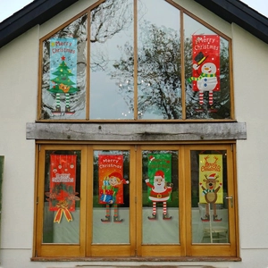 Outdoor view of festive hanging banners with Santa and Reindeer on large glass windows