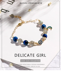 Detail of beaded bracelet with blue moonstone, evil eye charm and gold moon pendant