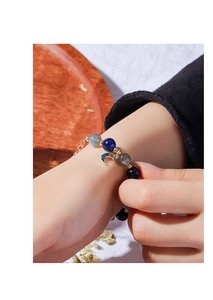 Detailed close-up of blue and grey beaded bracelet with moon charm on woman wrist