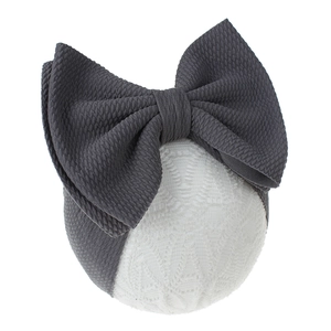 Detailed view of large grey waffle knit bow headband for babies on a display stand
