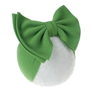 Detailed view of green baby headband featuring oversized bow and textured bullet fabric