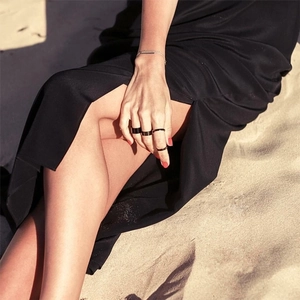 Minimalist black stainless steel rings and bracelet set worn by a model at the beach