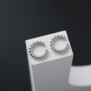 Detail shot of silver beaded C-shaped ear cuffs on geometric stone display stand