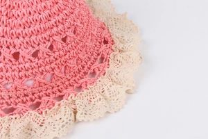 Detailed close-up of dark pink woven straw hat featuring white lace trim and intricate patterns