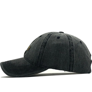 Close-up of charcoal grey washed denim baseball cap with gold lion embroidery detail