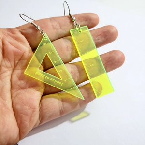 Close-up of hand holding fluorescent yellow acrylic triangle and ruler earrings