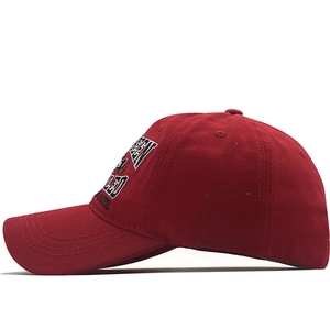 Dettaglio del cappellino da baseball in cotone rosso scuro con toppe ricamate a lettere