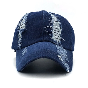 Distressed dark blue denim baseball cap with vintage frayed holes and street style