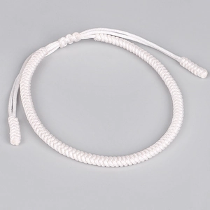 Detail of hand-woven white knot bracelet with intricate textile texture and adjustable cord