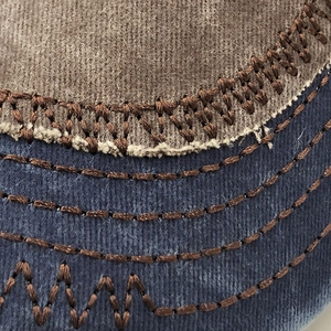Macro detail of washed baseball cap fabric with heavy industrial stitching and contrast colors