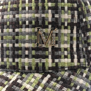 Detail of green tweed texture baseball cap featuring a crystal-inlaid metal M logo