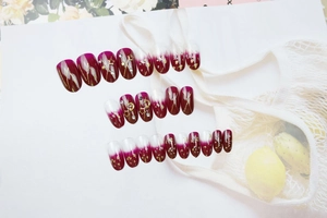 Detailed view of burgundy gradient press-on nails with gold star and moon embellishments