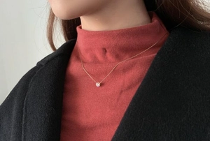 Close-up of a 18K gold plated titanium necklace with a sparkling zircon pendant on a model
