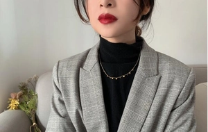 Close-up of minimalist gold disc pendant necklace worn on a professional chic outfit