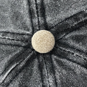 Macro shot of cotton denim baseball cap top with textured fabric and beige button