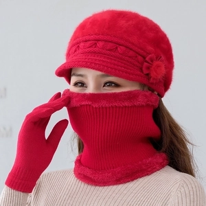 Detailed view of red knitted winter hat set with floral accent and faux fur lining