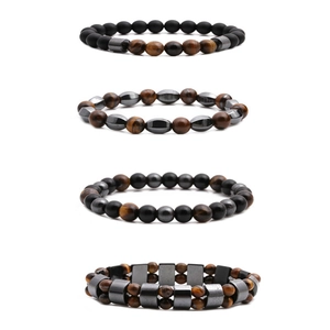 Detail of stacked tiger eye and hematite beaded bracelets with matte black stones