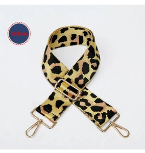 Close-up of yellow leopard print bag strap with golden metal clasps and thick fabric