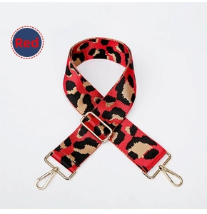 Detail of red leopard print woven bag strap with adjustable metal buckle and lobster clips