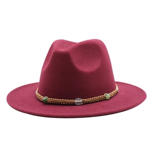 Detail of burgundy fedora hat with braided rope band and green beads on white background