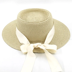 Top view of a straw boater hat featuring a large creamy white satin ribbon bow detail