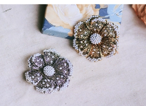 Detailed view of vintage hollow flower brooches with pearls in gold and silver finish