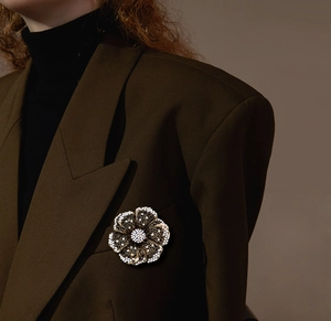 Detail view of a vintage pearl flower brooch pinned to a professional brown blazer lapel
