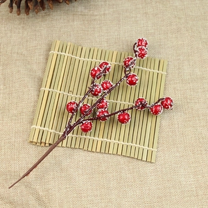 Close-up of red artificial frosted berries branch with snow for Christmas tree decor