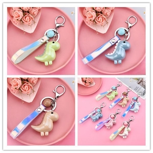Close-up of cute dinosaur keychains in vibrant colors with iridescent gradient wrist straps