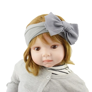 Soft grey knotted baby headband with a large textured bow on a baby model
